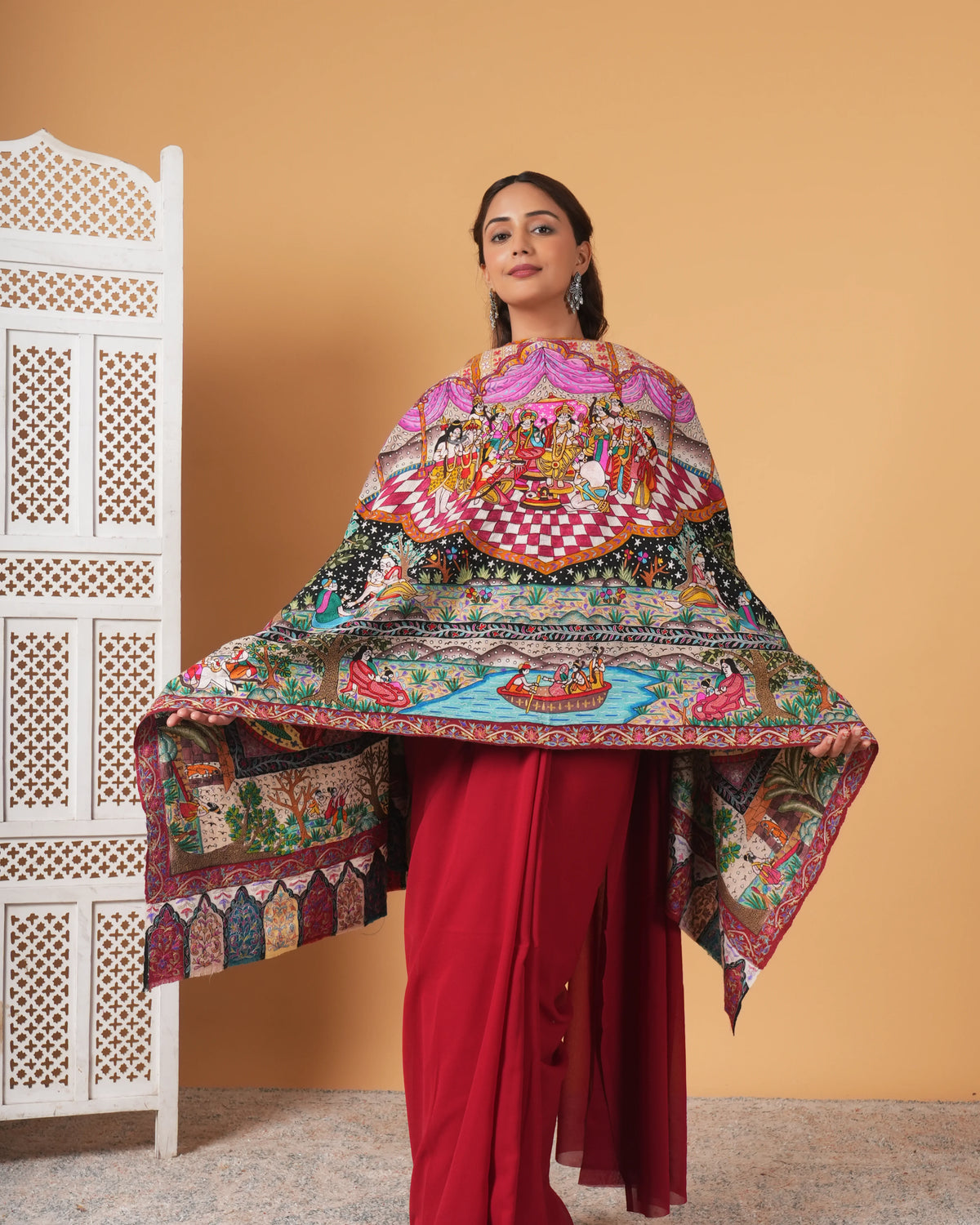 Woman wearing a colorful traditional outfit with a patterned shawl against a beige background