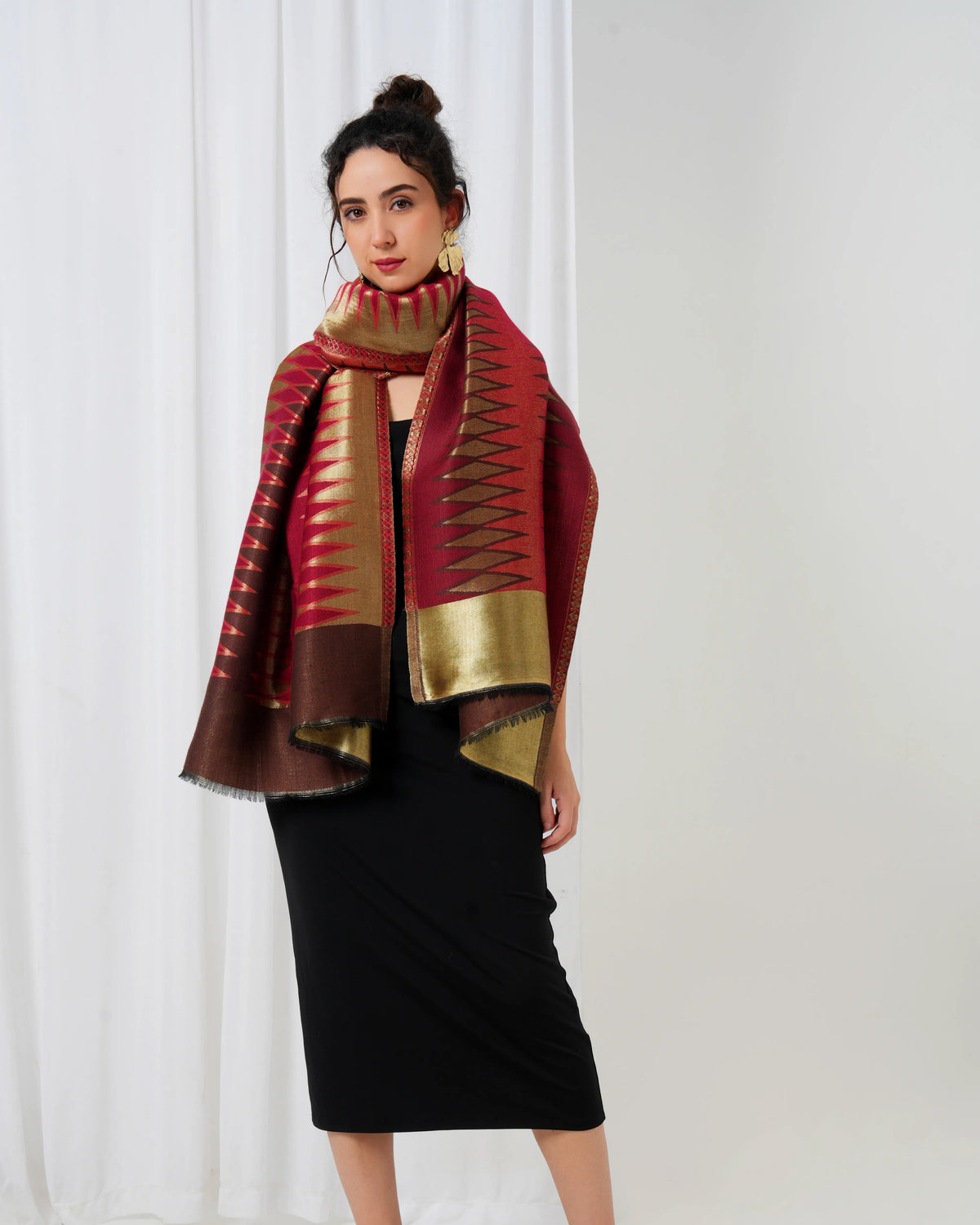 Woman wearing a red and gold patterned scarf against a white background
