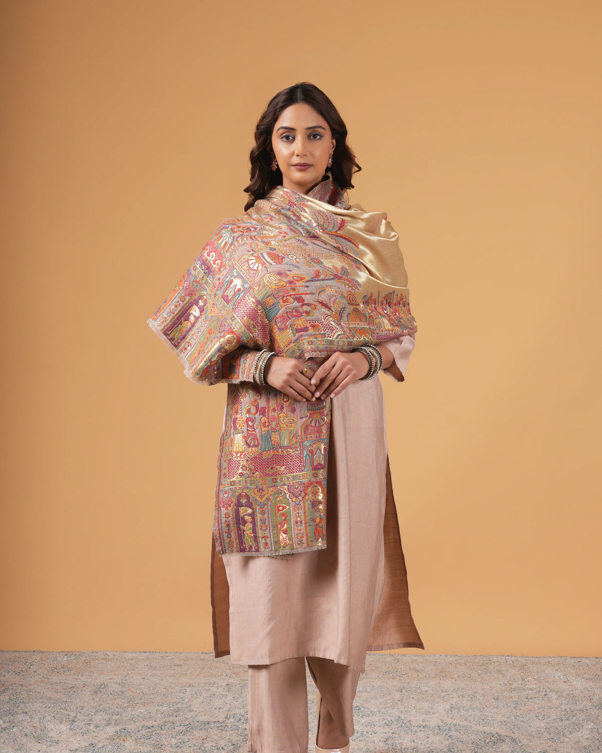 Woman wearing a traditional outfit with a patterned shawl against a beige background