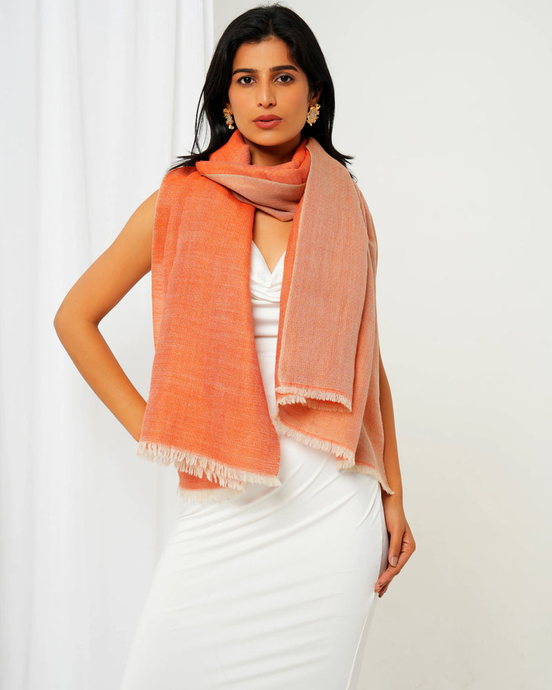 Woman wearing a peach scarf over a white outfit against a white background