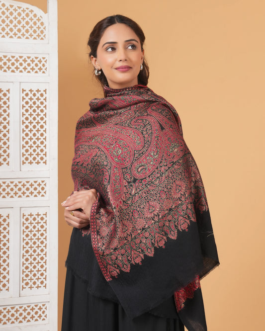 Woman wearing a patterned shawl against a beige wall
