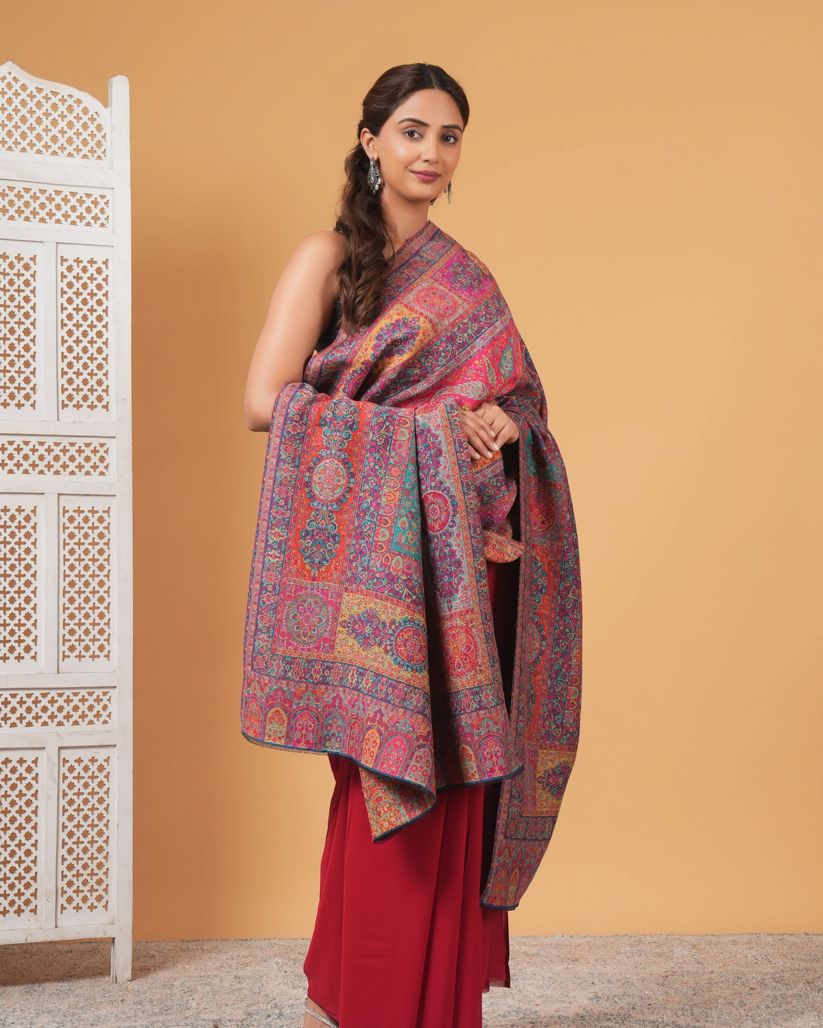 Woman holding a patterned scarf against a beige wall