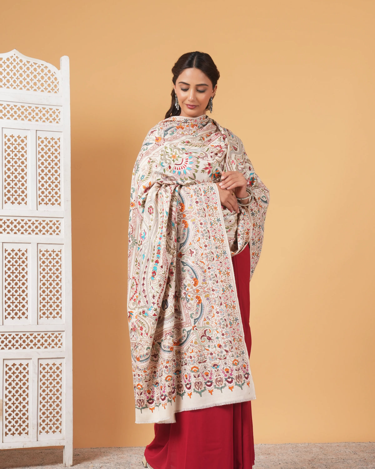 Woman wearing a floral patterned dupatta over a red outfit against a beige background