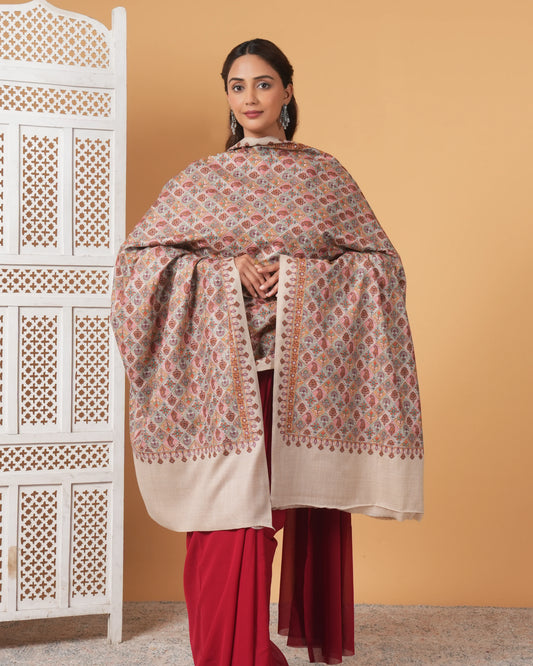 Woman wearing a patterned shawl over a plain garment against a beige background