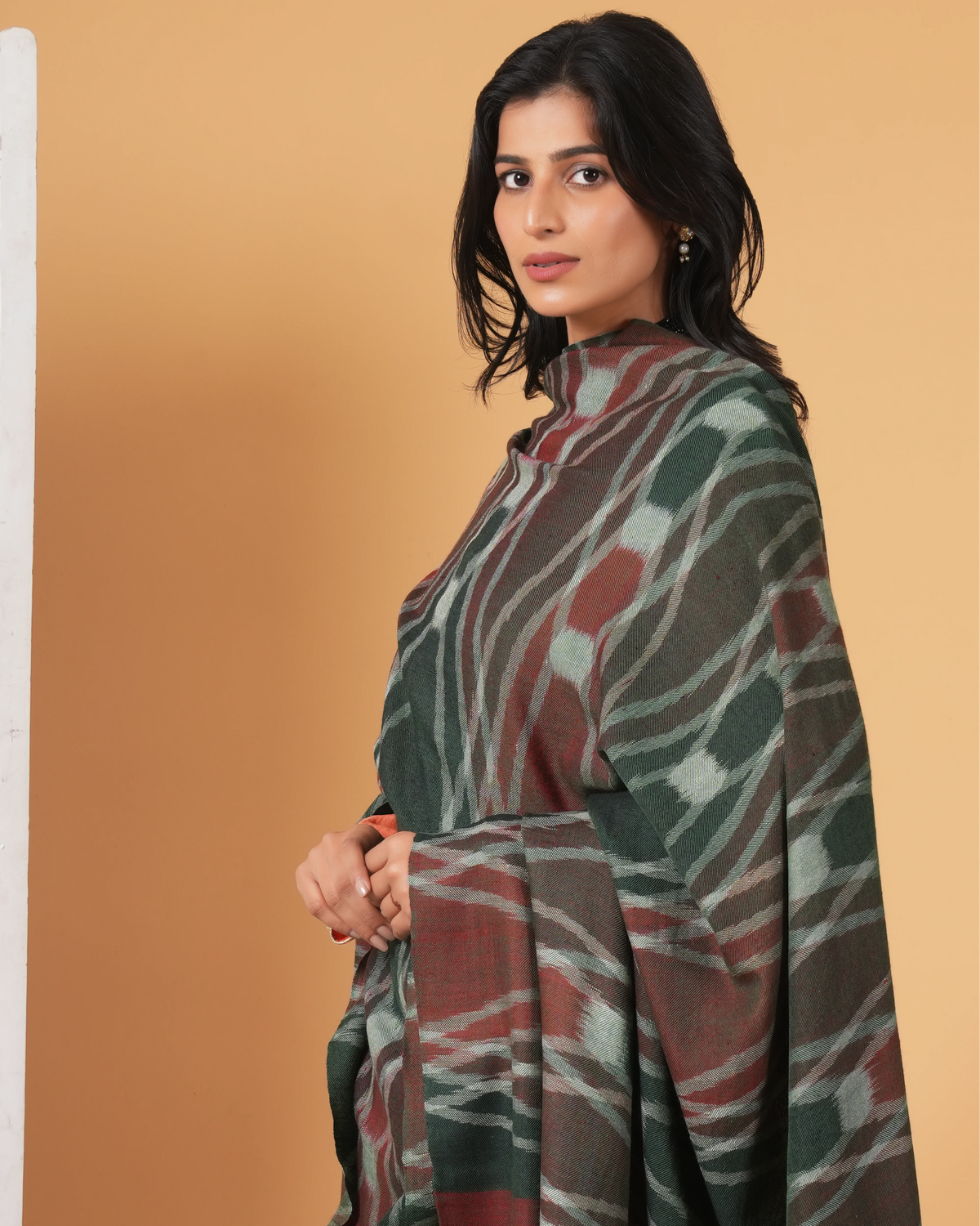 Woman wearing a patterned shawl against a beige background