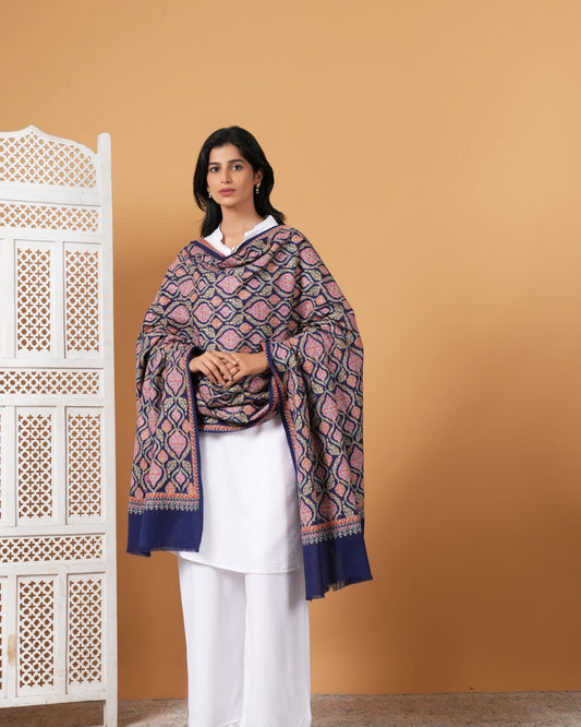 Woman wearing a patterned shawl over a white outfit against a beige background