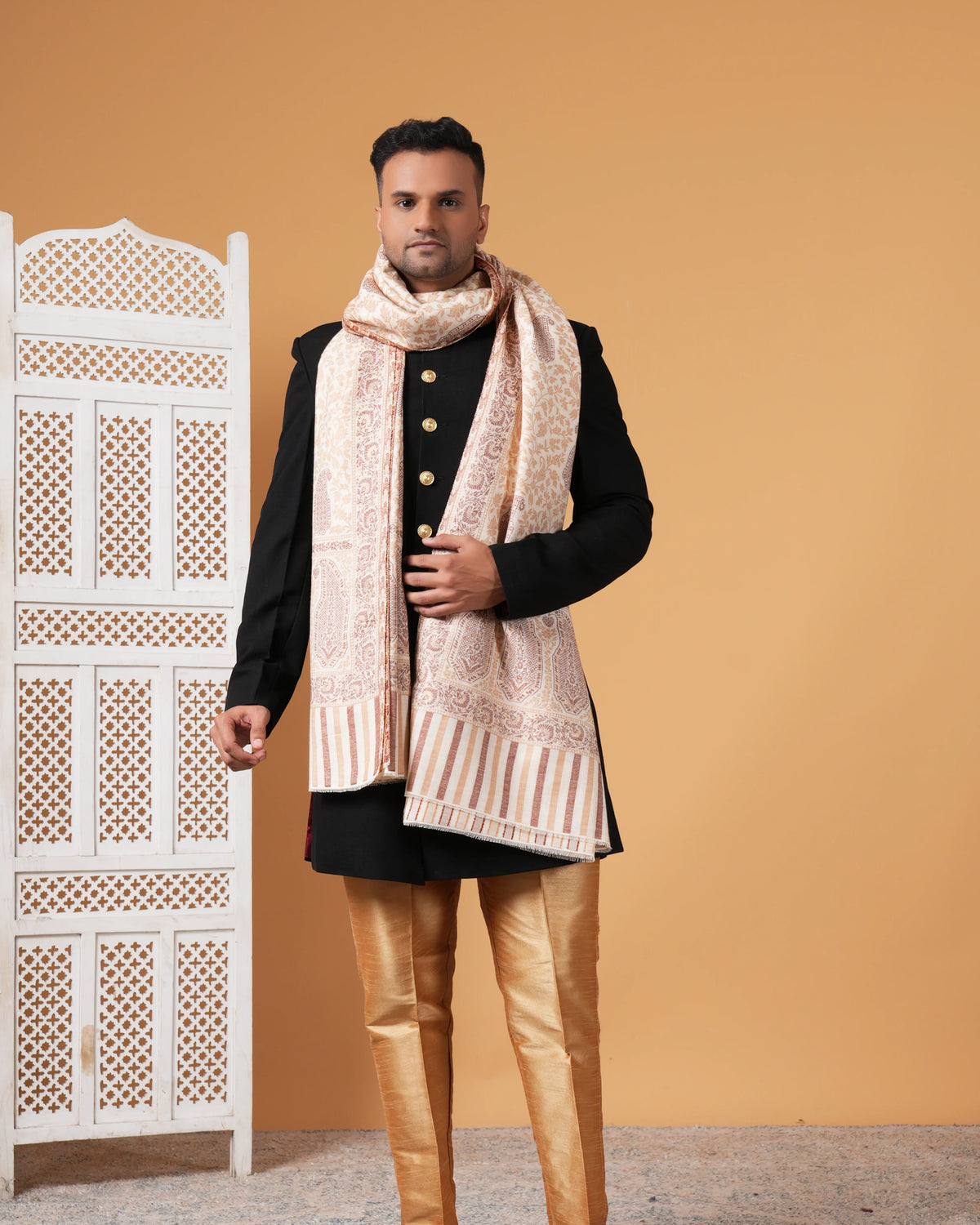 Man wearing a traditional outfit with a patterned scarf against a beige background