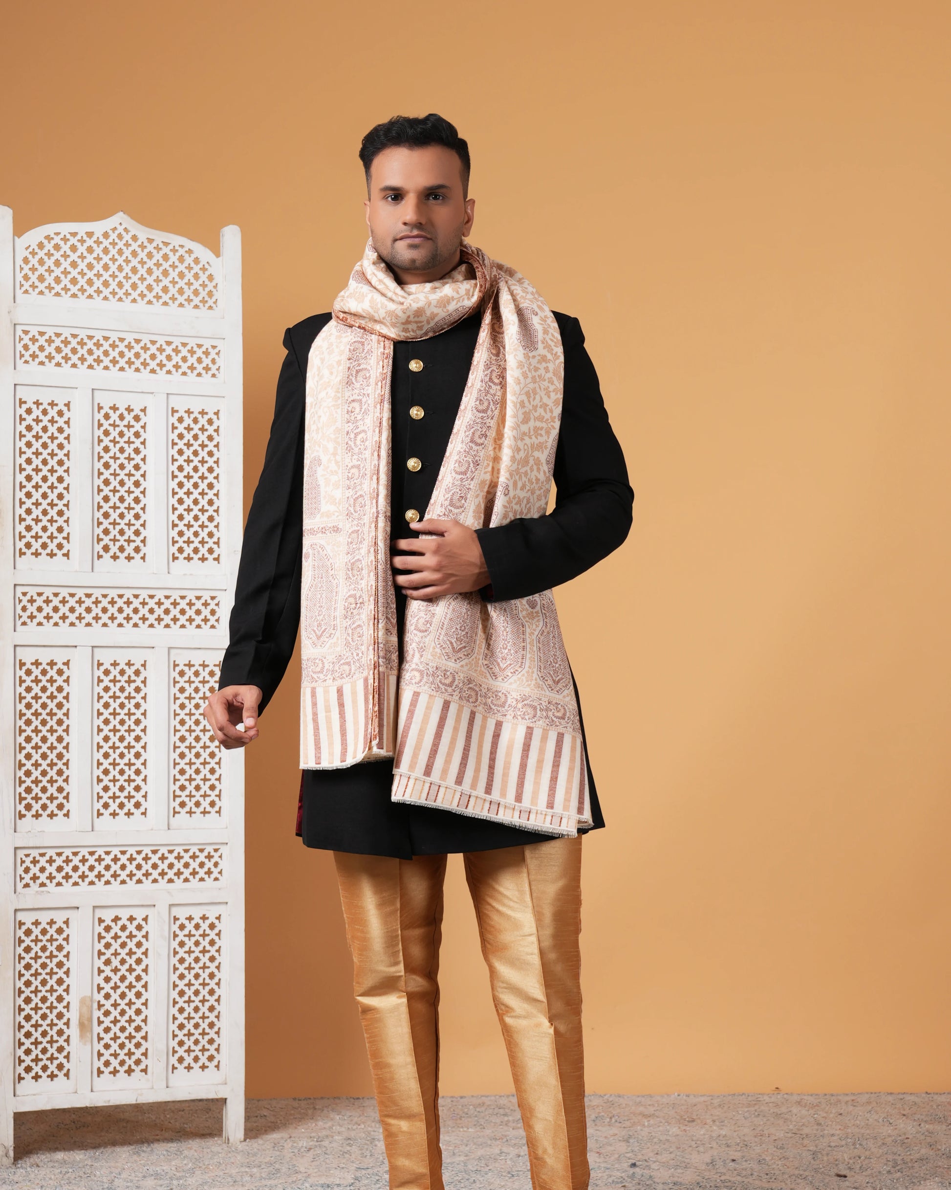 Man wearing a traditional outfit with a patterned scarf against a beige background