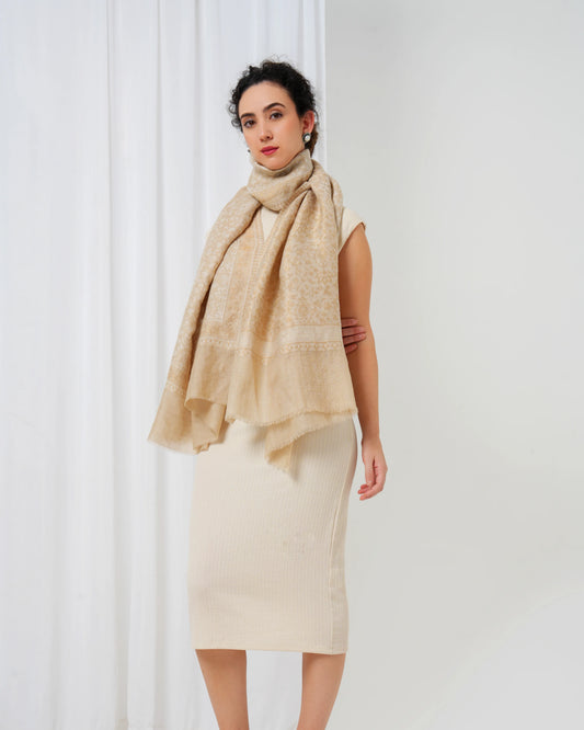 Woman wearing a beige scarf and dress against a white curtain background