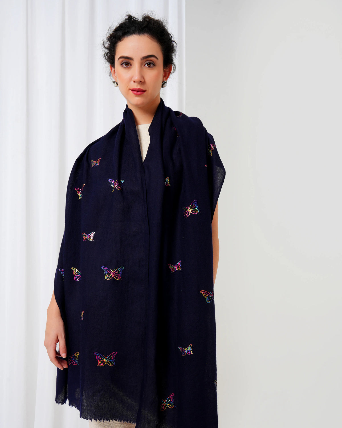 Woman wearing a dark blue scarf with colorful butterfly patterns against a white background