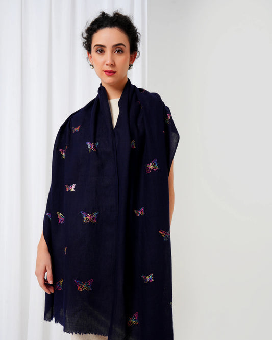 Woman wearing a dark blue scarf with colorful butterfly patterns against a white background