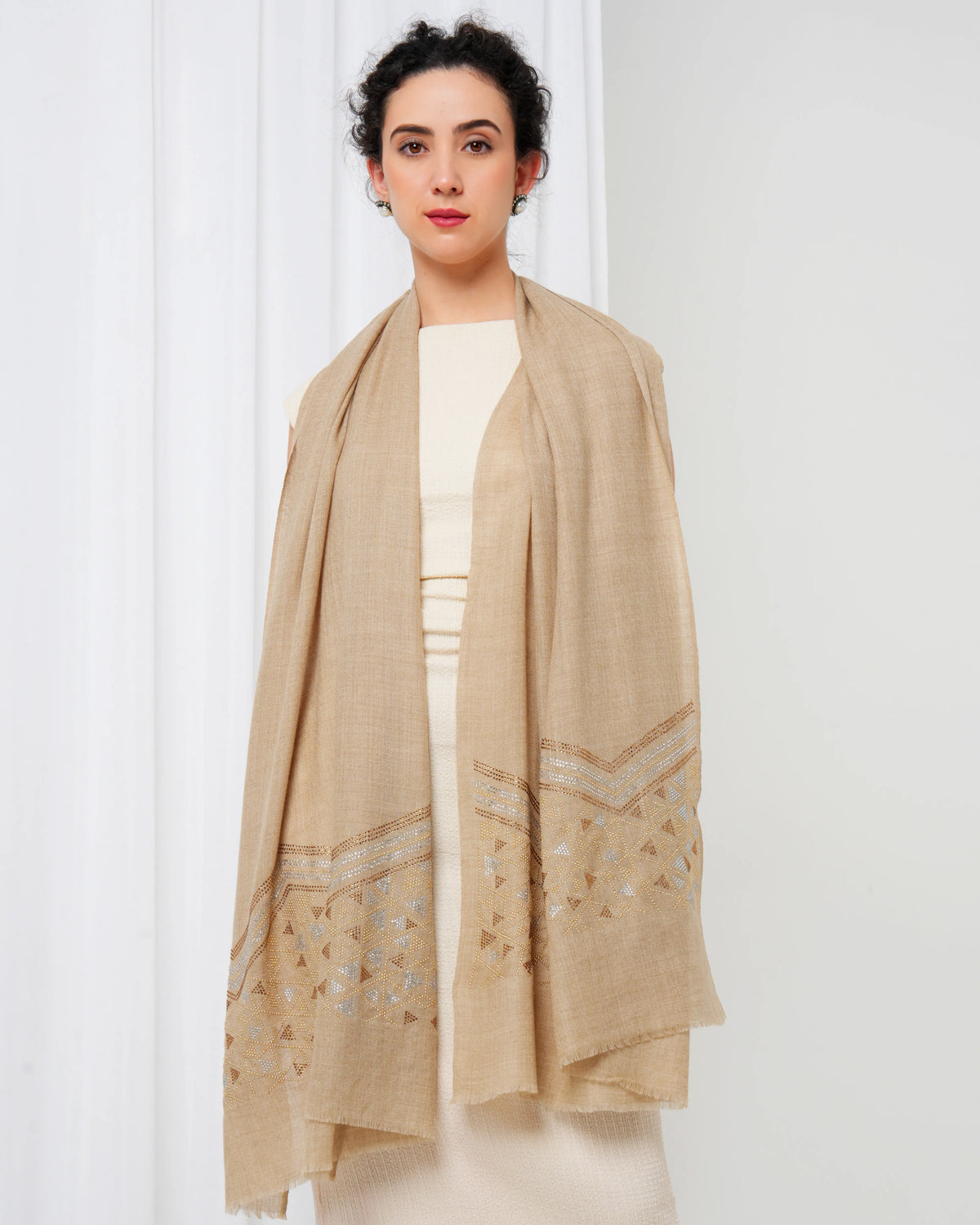 Woman wearing a beige shawl with intricate patterns on a white background