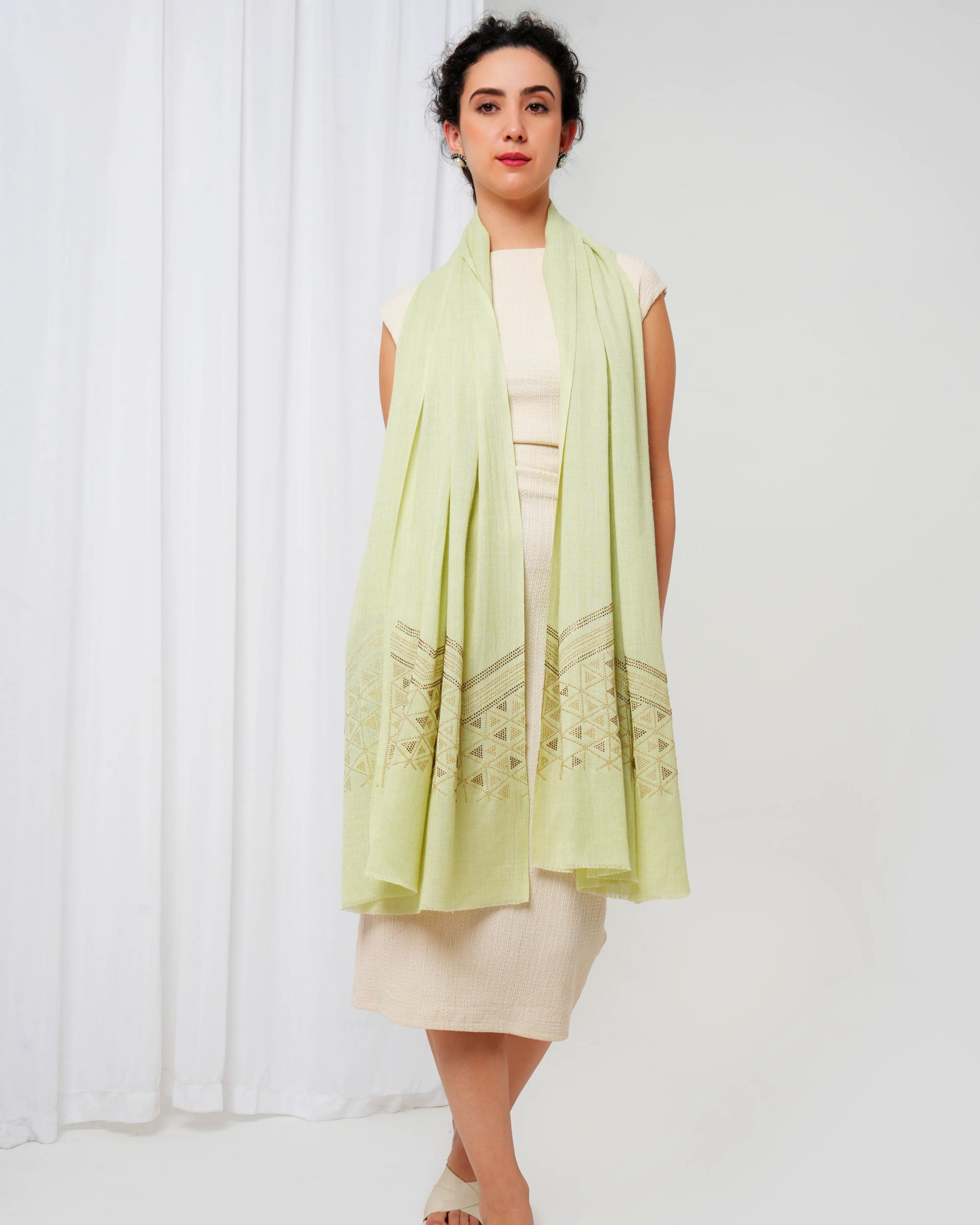 Woman wearing a light green scarf over a white dress against a white background