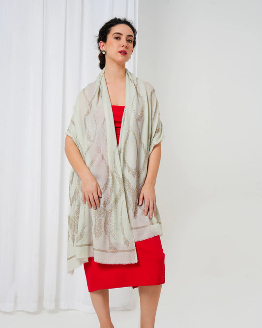 Woman wearing a light-colored scarf over a red dress against a white curtain background