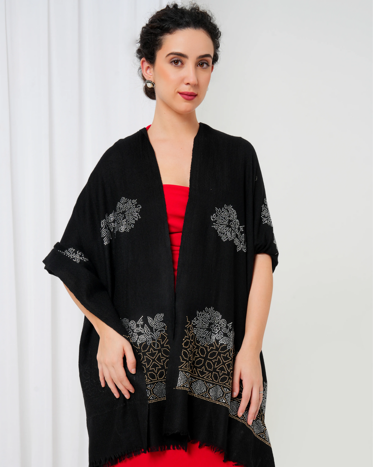 Woman wearing a black embroidered kimono-style garment with a white background