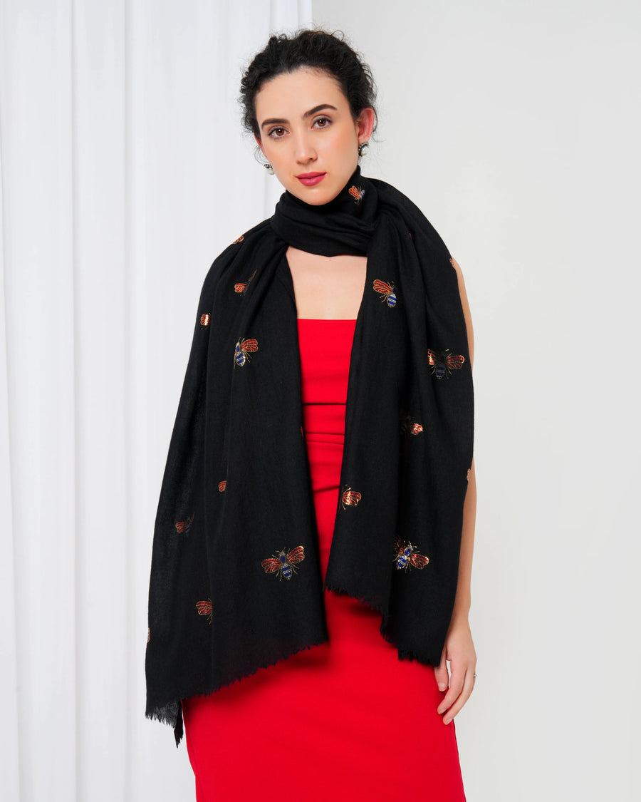 Woman wearing a black scarf with brown embellishments over a red dress against a white background