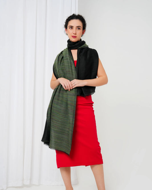 Woman wearing a green scarf, black top, and red skirt against a white background
