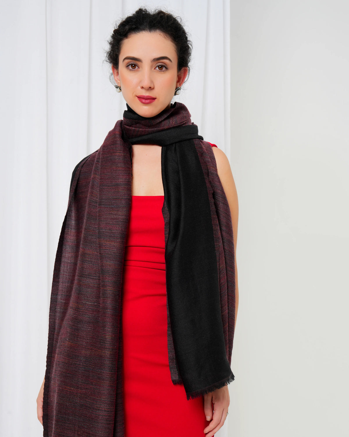 Woman wearing a red dress and a large brown scarf against a white background