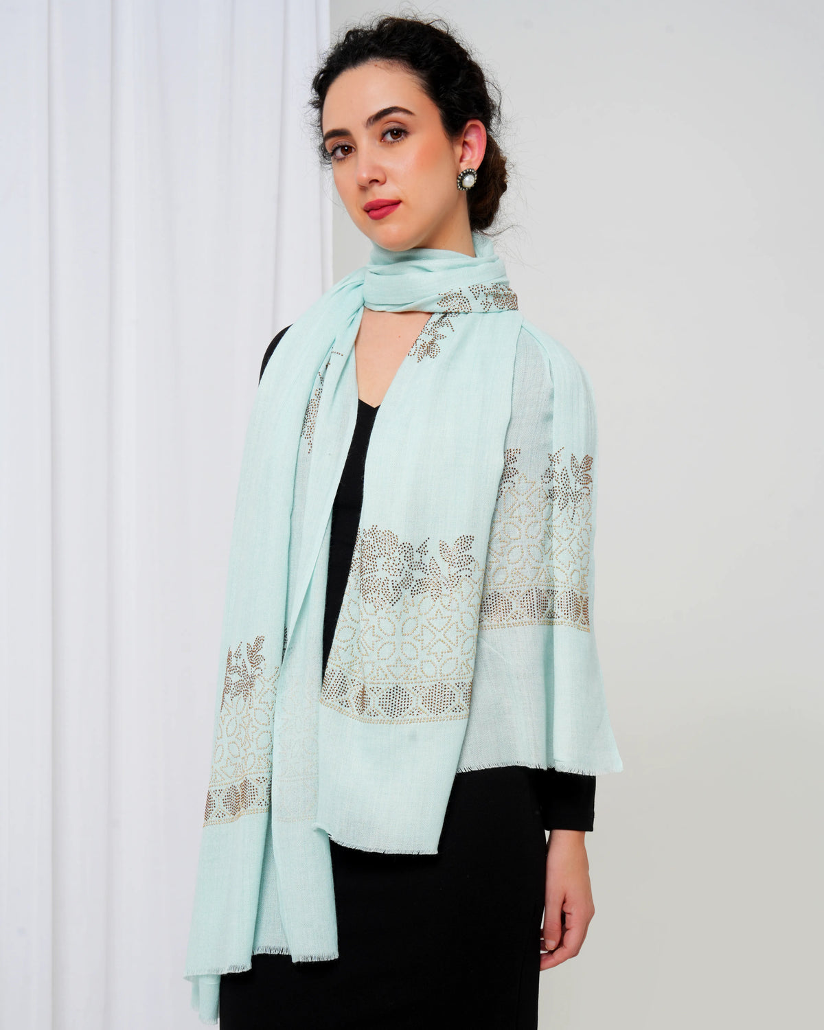 Woman wearing a light blue scarf with floral patterns against a white background