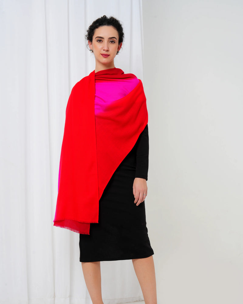 Woman wearing a red and pink shawl over a black dress against a white curtain background