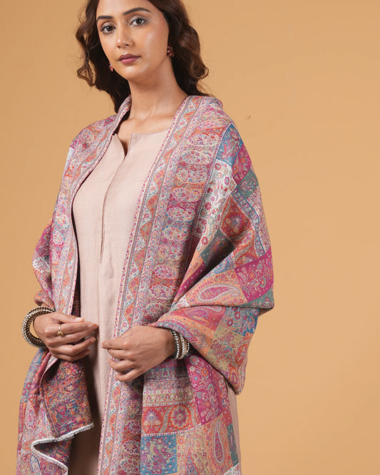 Woman wearing a patterned shawl over a plain top against a beige background