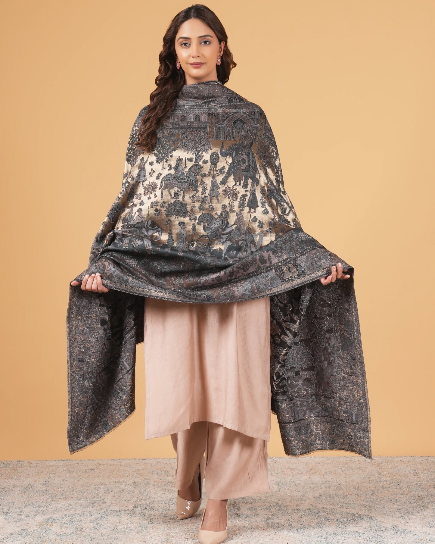 Woman wearing a dark patterned shawl over a beige outfit against a beige background
