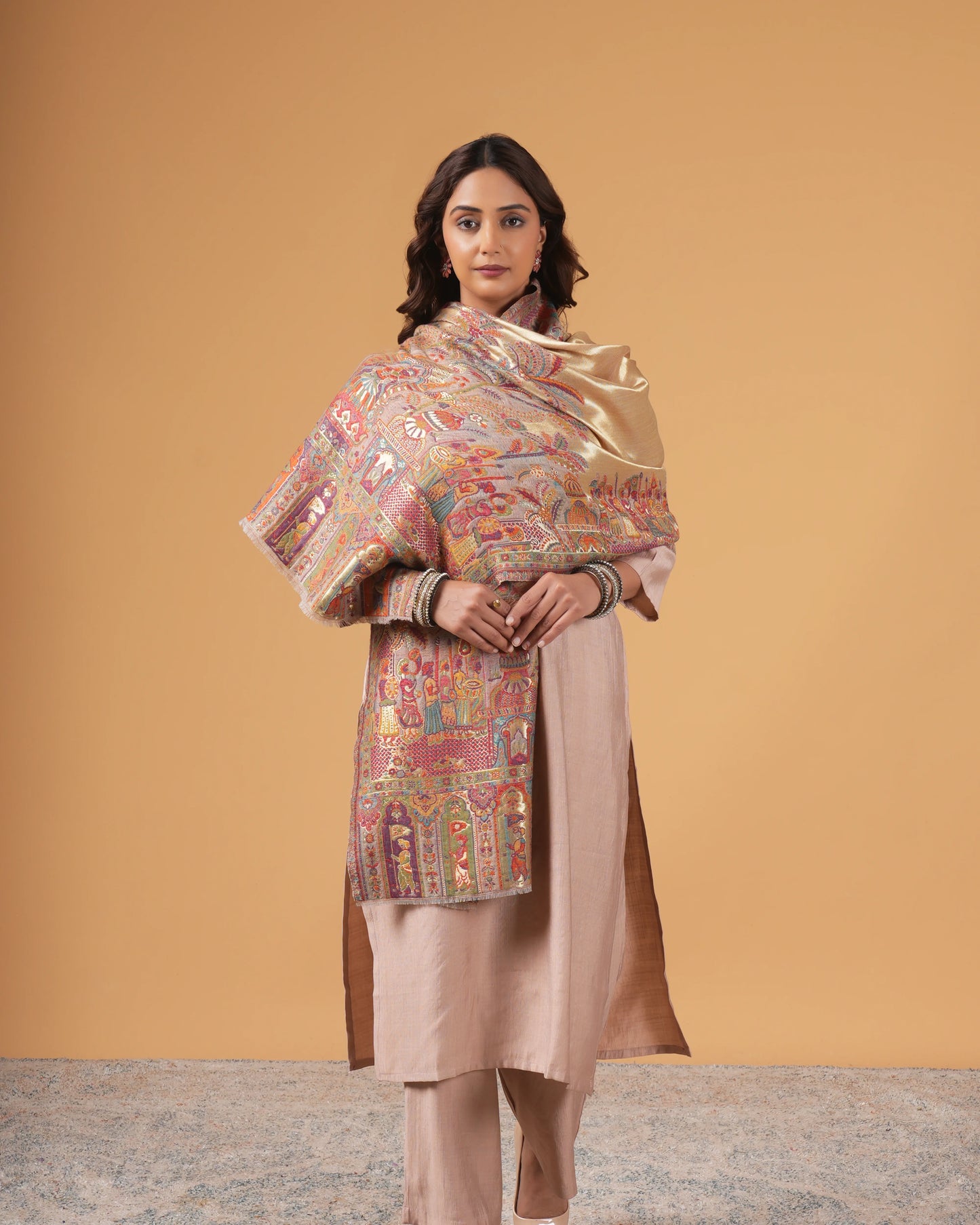 Woman wearing a traditional outfit with a patterned shawl against a beige background