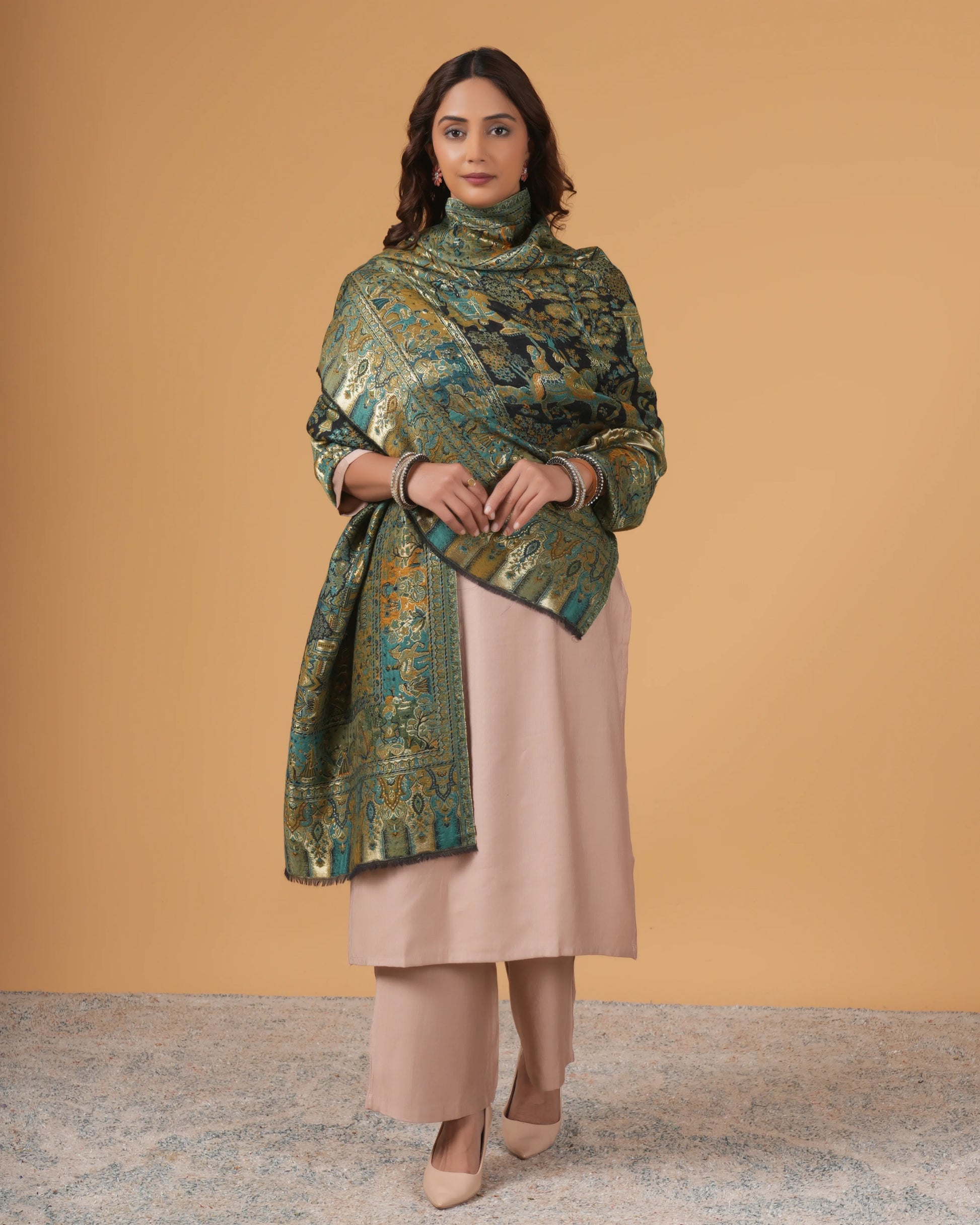 Woman wearing a green patterned shawl over a beige outfit against a beige background