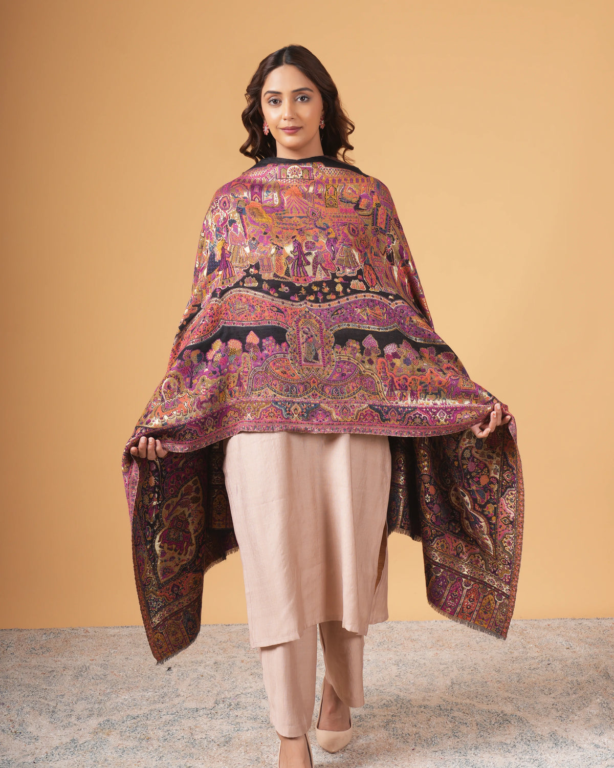 Woman wearing a colorful patterned shawl over a plain outfit against a beige background