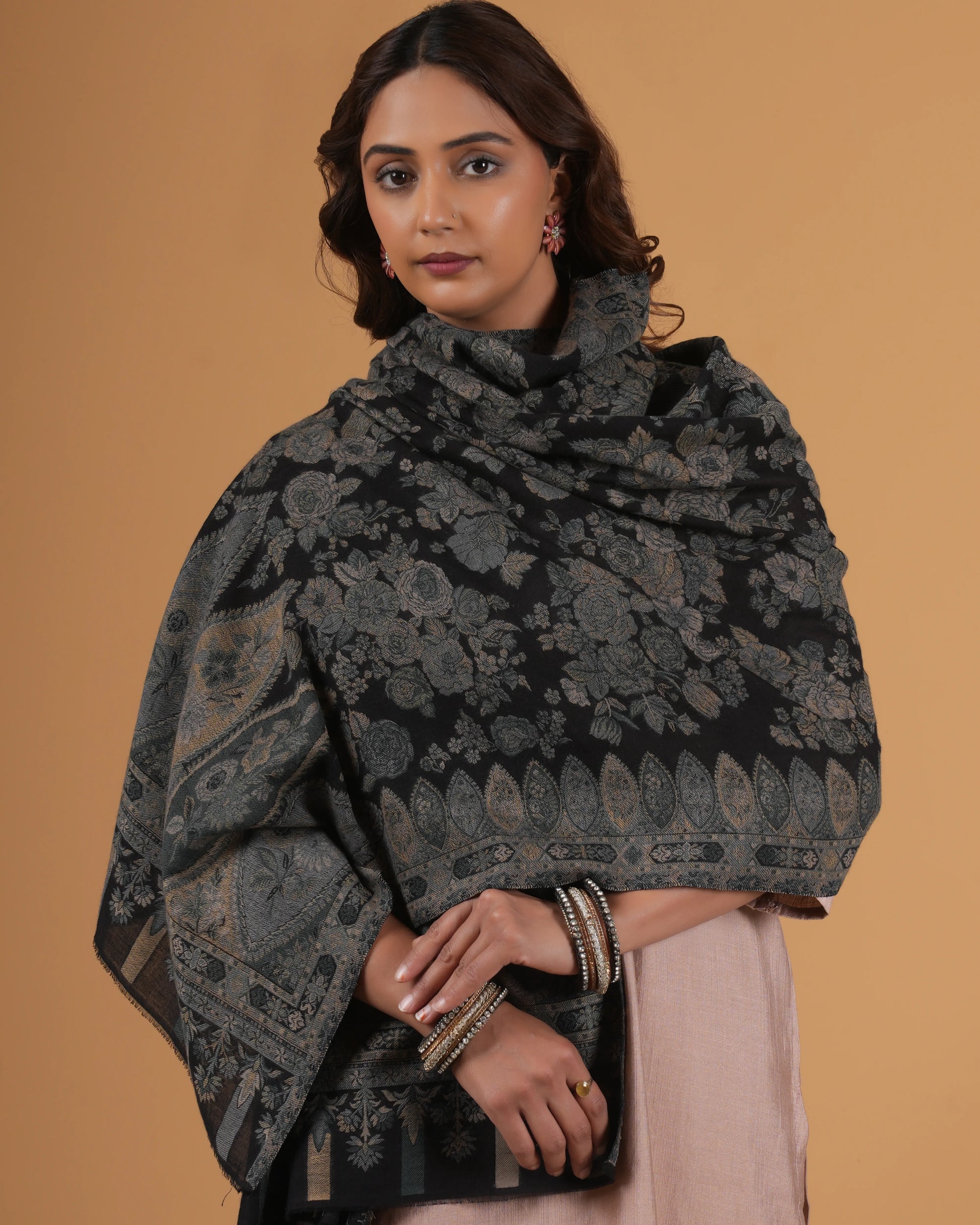 Woman wearing a dark floral patterned shawl against a beige background