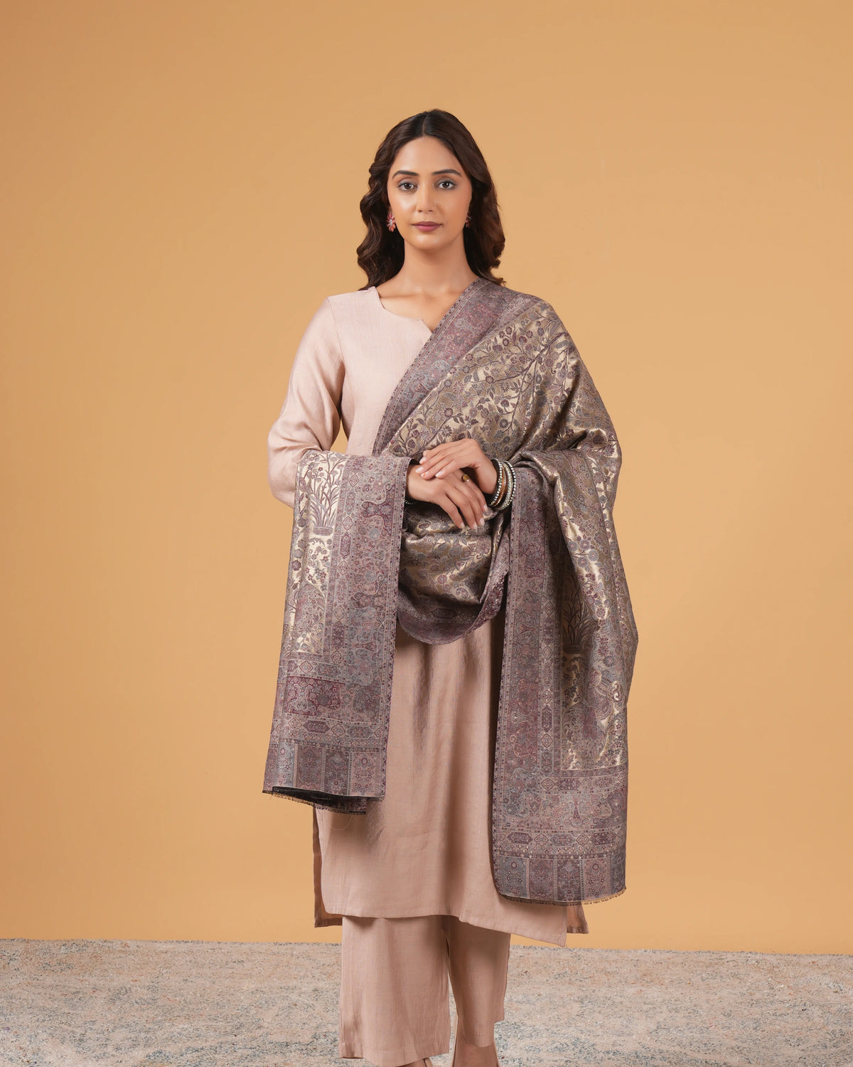 Woman holding a patterned shawl against a beige background