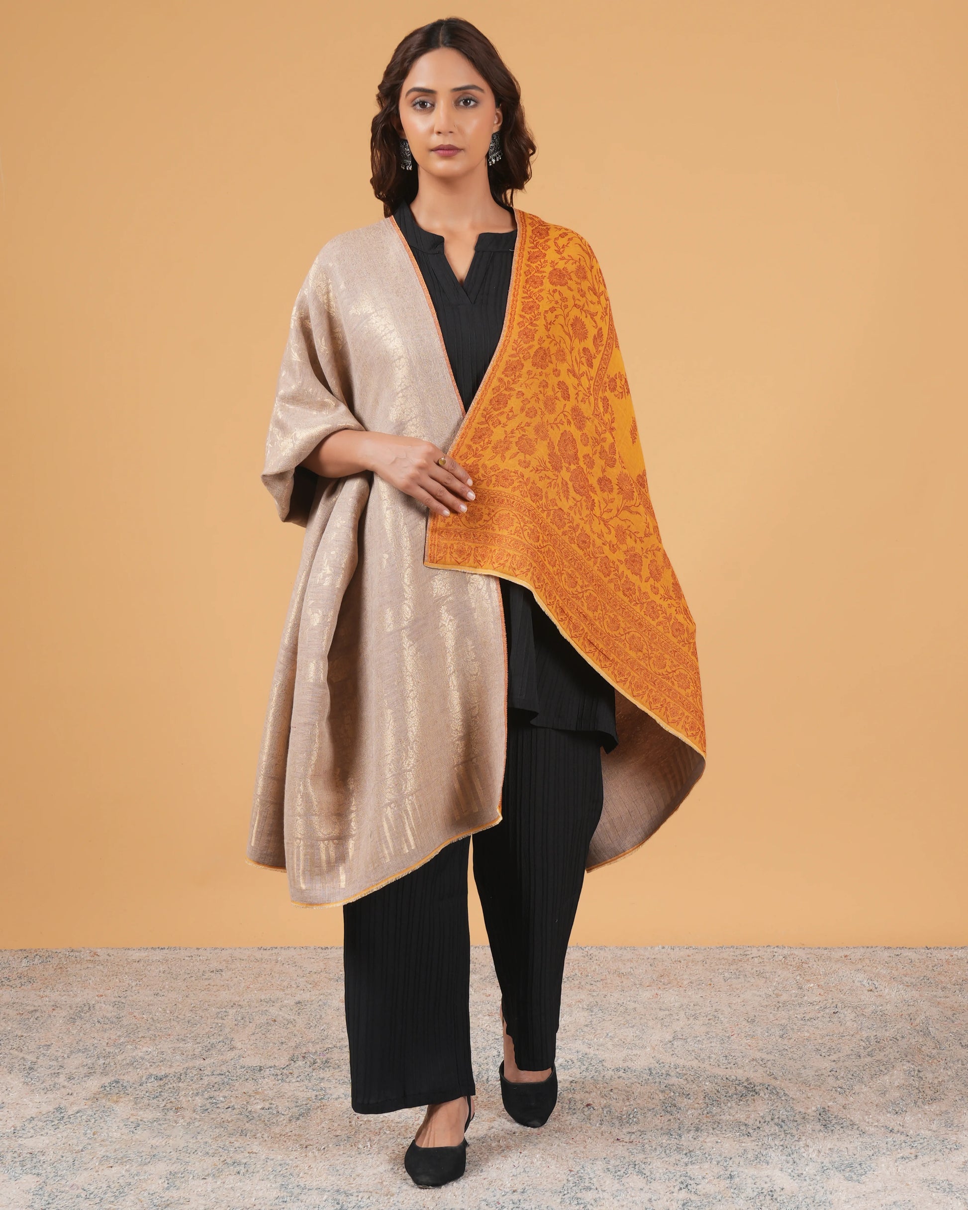 Woman wearing a beige and orange shawl against a beige background