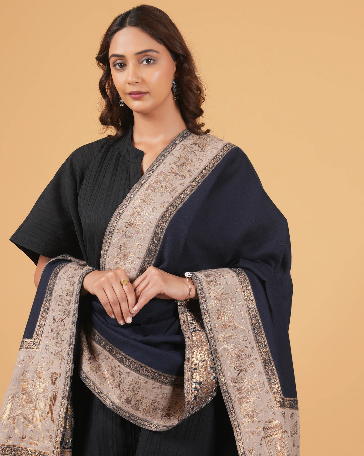 Woman wearing a black outfit with a patterned shawl on a beige background