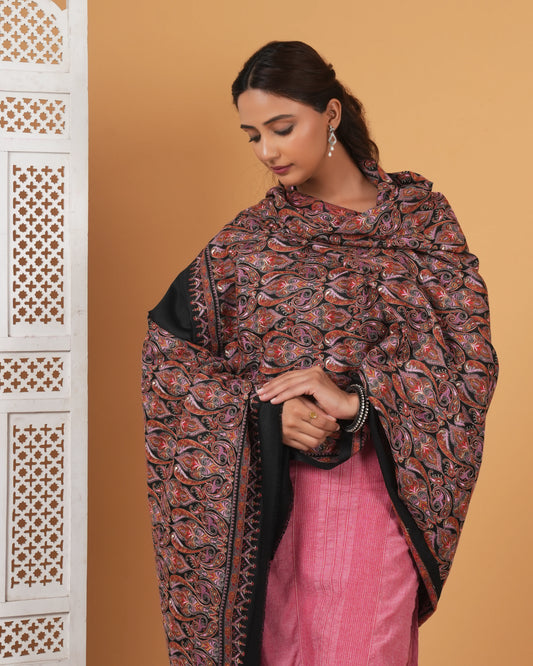 Woman wearing a patterned shawl over a pink outfit against a beige background