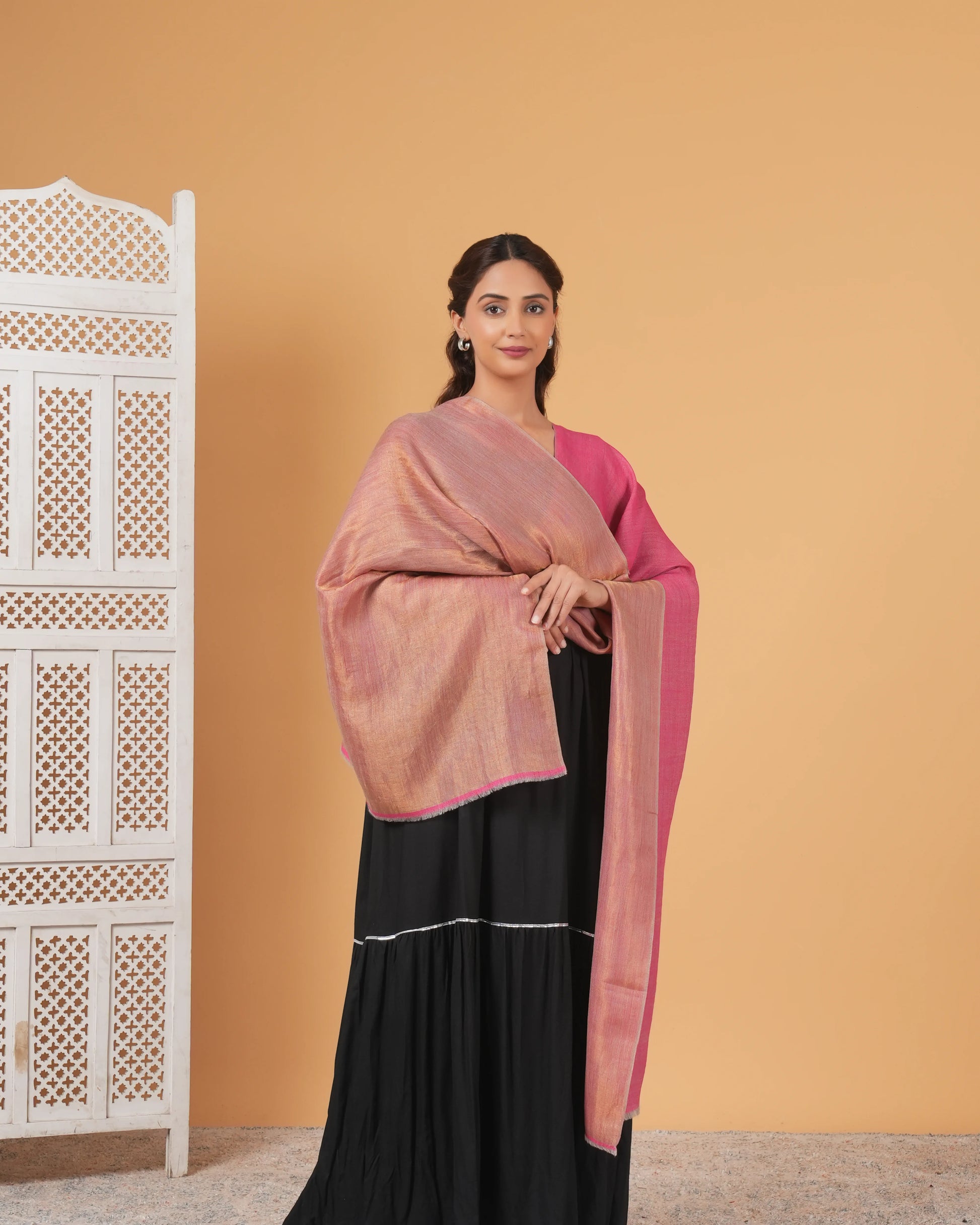 Woman wearing a pink and black traditional outfit against an orange wall.